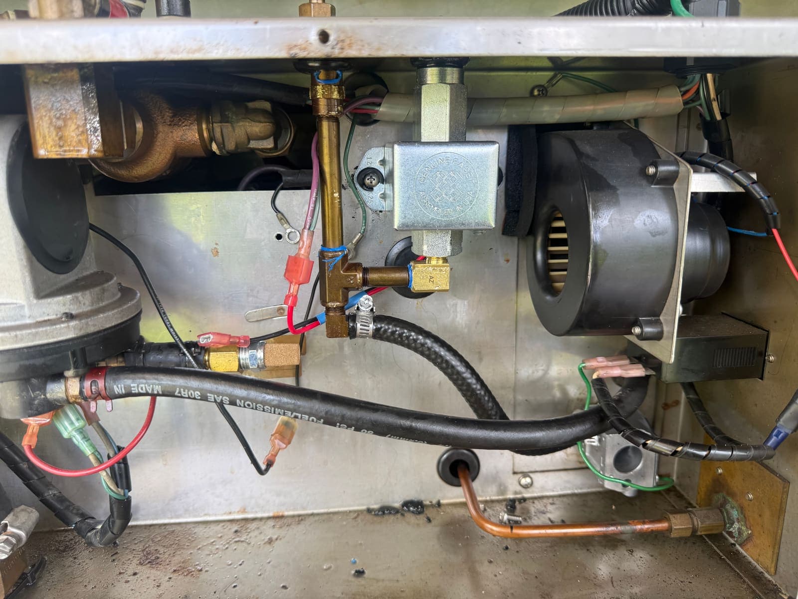 Internal RV appliance components showing blower fan, fuel lines, and wiring during repair